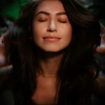 Woman with eyes closed, enjoying indoor atmosphere