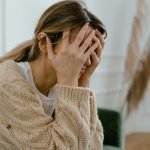 Woman Sitting with Hands Covering Her Face
